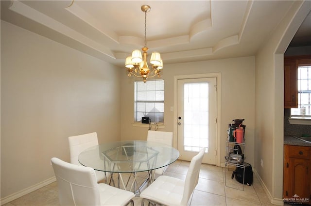 dining space with a raised ceiling, a notable chandelier, and light tile patterned flooring