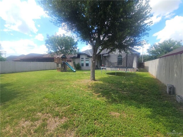 view of yard featuring a playground and a trampoline