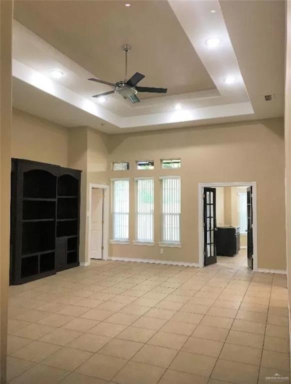 unfurnished room with a raised ceiling, ceiling fan, and a towering ceiling