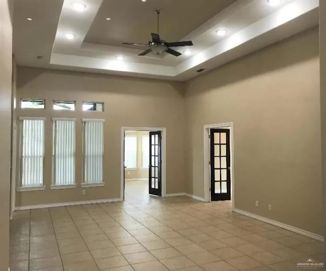 spare room with french doors, a raised ceiling, ceiling fan, a towering ceiling, and light tile patterned flooring