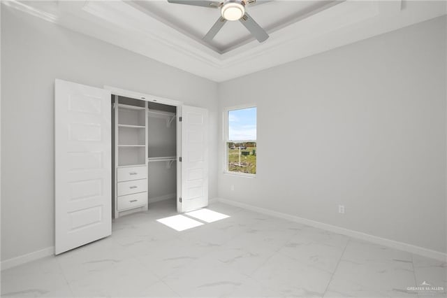 unfurnished bedroom featuring ceiling fan, a tray ceiling, and a closet