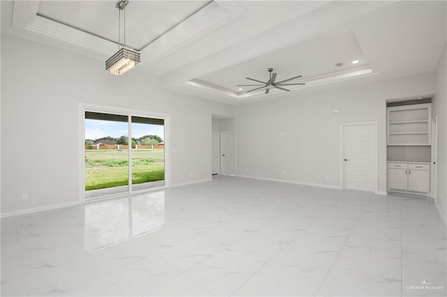 unfurnished room with built in shelves, a raised ceiling, and ceiling fan