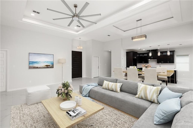 living room with ceiling fan and a raised ceiling