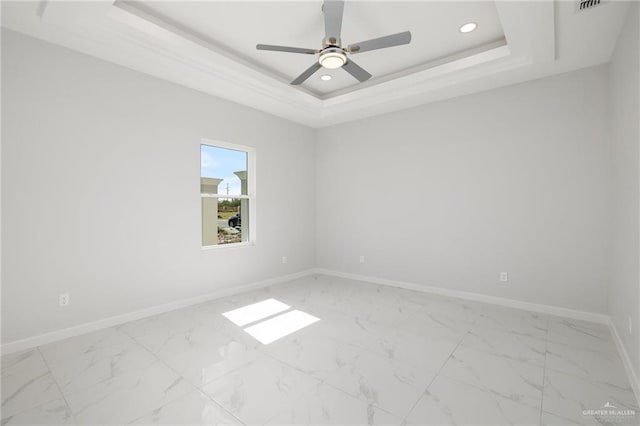 unfurnished room featuring a raised ceiling and ceiling fan