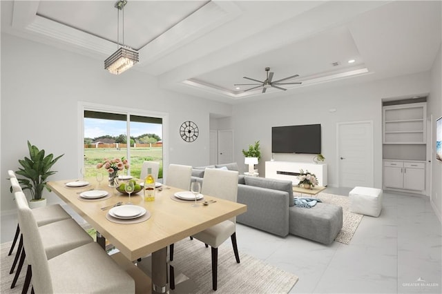 dining area featuring built in shelves, ceiling fan with notable chandelier, and a tray ceiling