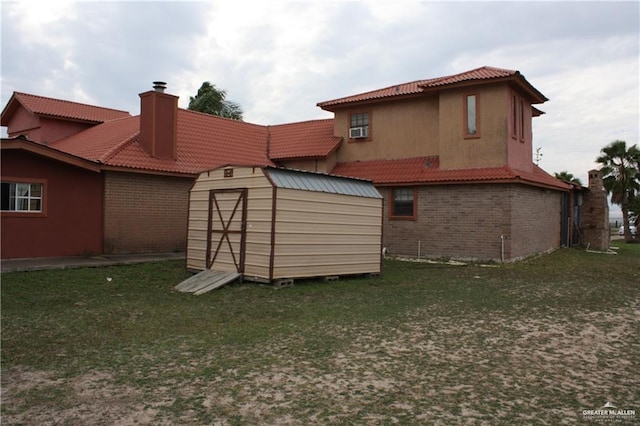 rear view of property featuring a yard, cooling unit, and a storage shed