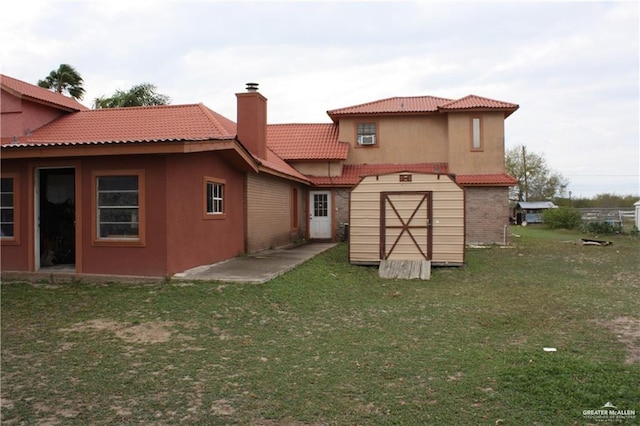 rear view of property featuring a yard, cooling unit, and a storage shed