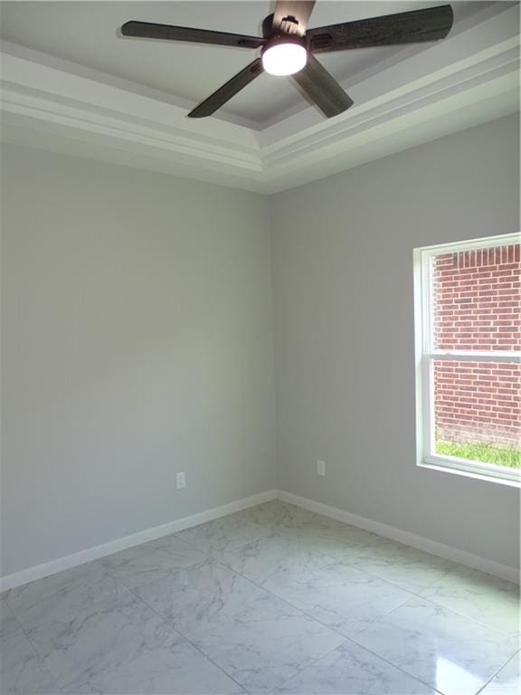 empty room with a raised ceiling, ceiling fan, and ornamental molding