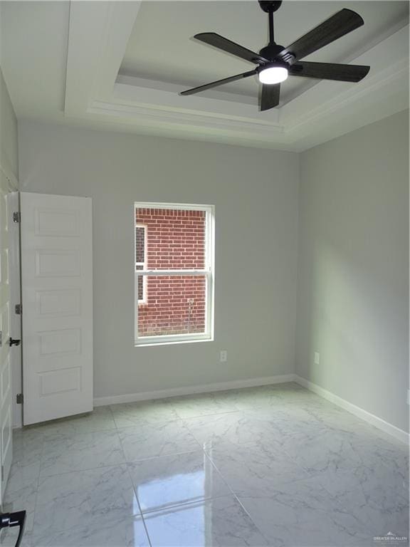 empty room with a tray ceiling, ceiling fan, and ornamental molding