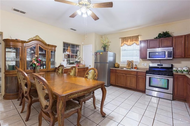 kitchen with appliances with stainless steel finishes, light tile patterned floors, ceiling fan, and sink