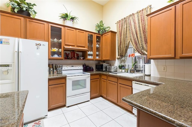 kitchen with dark stone countertops, white appliances, sink, and tasteful backsplash