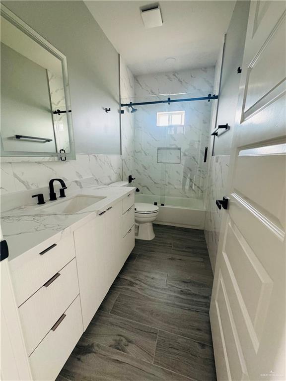 502 Pearl St, Edinburg, TX 78542 - bathroom featuring vanity, toilet, and a combined bath / shower with marble appearance