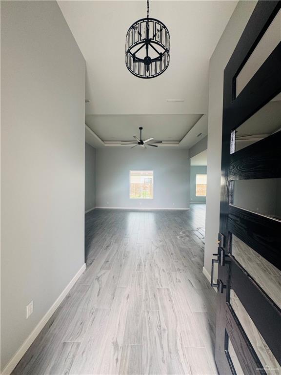 502 Pearl St, Edinburg, TX 78542 - spare room featuring a chandelier, wood finished floors, baseboards, and a ceiling fan