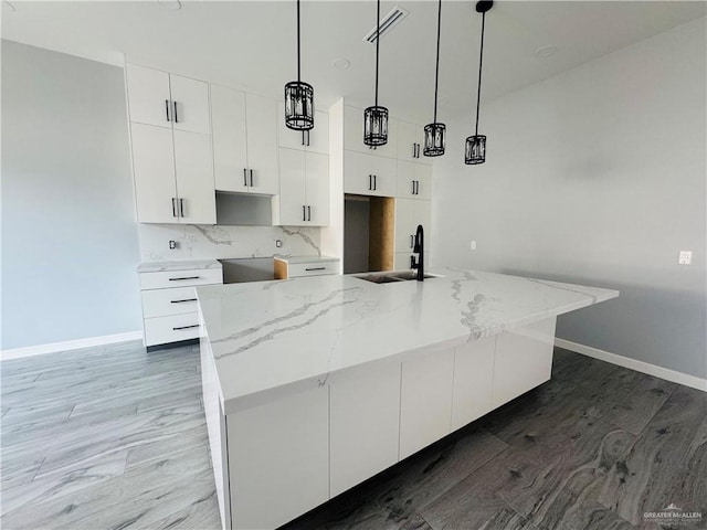 502 Pearl St, Edinburg, TX 78542 - kitchen featuring a sink, white cabinetry, baseboards, wood finished floors, and an island with sink