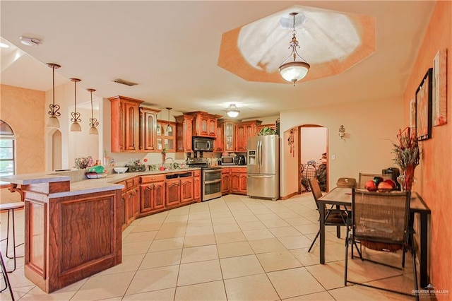 1722 Blue Bird Ave, Penitas, TX 78576 - kitchen with stainless steel appliances, arched walkways, a peninsula, a kitchen bar, and brown cabinets