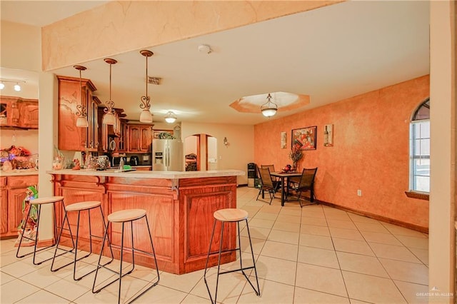 1722 Blue Bird Ave, Penitas, TX 78576 - kitchen featuring stainless steel fridge with ice dispenser, arched walkways, light tile patterned floors, a peninsula, and a breakfast bar