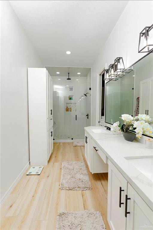 bathroom featuring hardwood / wood-style flooring, vanity, and a shower with shower door