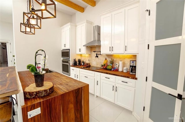 kitchen with beamed ceiling, butcher block counters, wall chimney range hood, and stainless steel appliances