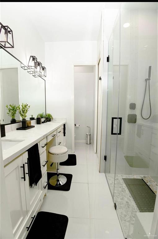 bathroom featuring a shower with door, vanity, and tile patterned flooring