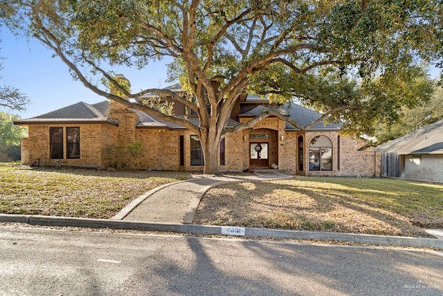 4301 Spring Creek Dr, Corpus Christi, TX 78410 - view of front of home with brick siding, a front lawn, and a chimney