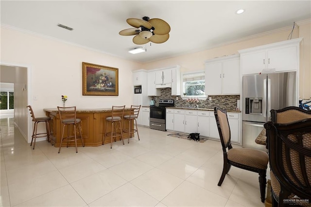 kitchen featuring plenty of natural light, white cabinetry, a breakfast bar, and appliances with stainless steel finishes