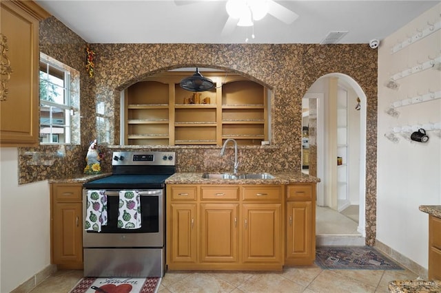 kitchen with stainless steel electric stove, ceiling fan, sink, and stone countertops