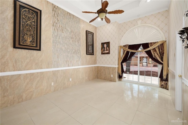 empty room featuring ceiling fan, crown molding, and tile patterned flooring