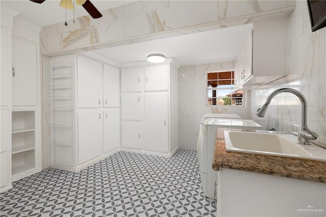 interior space with ceiling fan, cabinets, separate washer and dryer, and sink