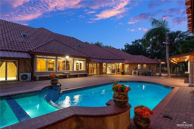 pool at dusk featuring ac unit and a patio area