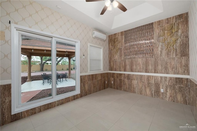 unfurnished room with ceiling fan, a raised ceiling, and an AC wall unit