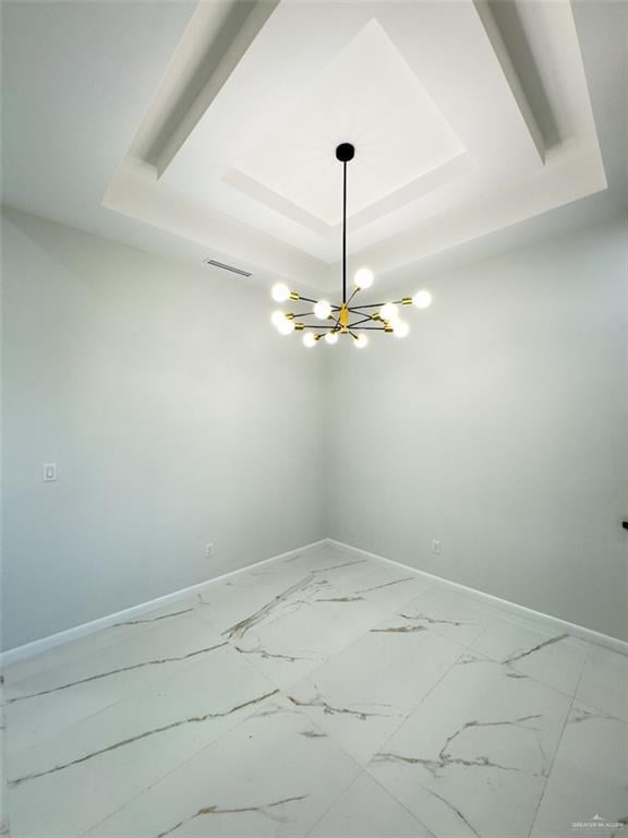 unfurnished room featuring visible vents, an inviting chandelier, baseboards, and a tray ceiling