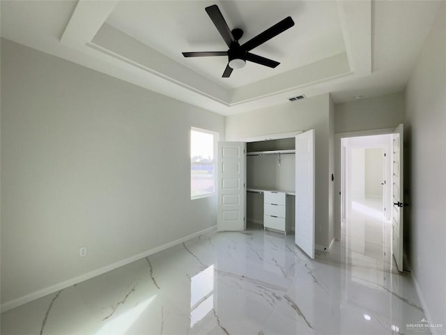 unfurnished bedroom with a tray ceiling, baseboards, and visible vents