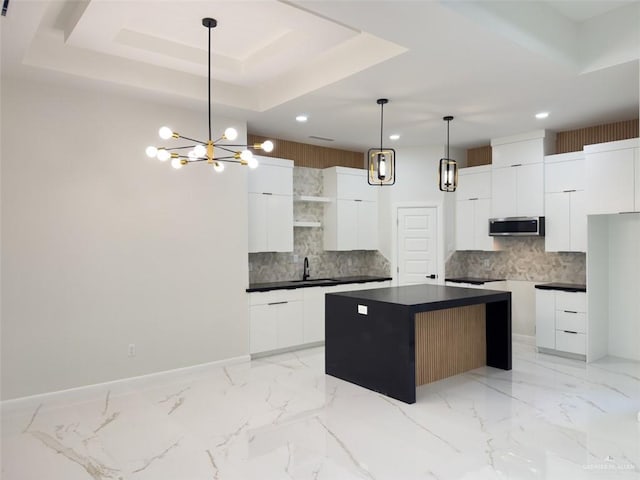 kitchen featuring stainless steel microwave, modern cabinets, a raised ceiling, and a sink