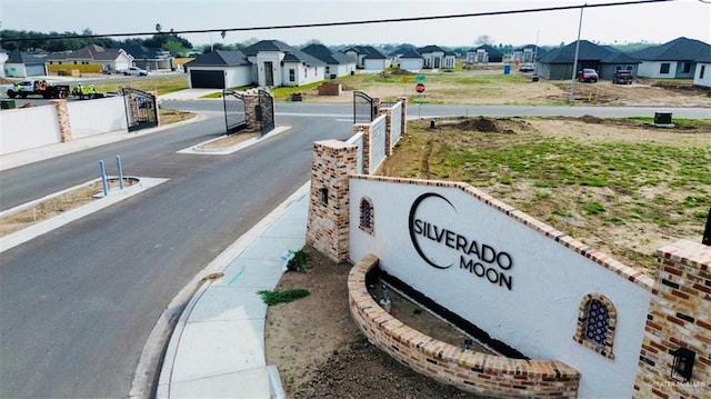 view of street featuring a gated entry, a residential view, curbs, sidewalks, and traffic signs