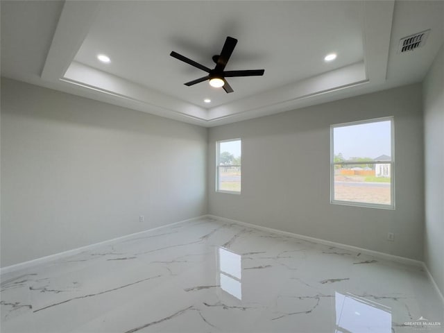 empty room featuring recessed lighting, a tray ceiling, baseboards, and visible vents