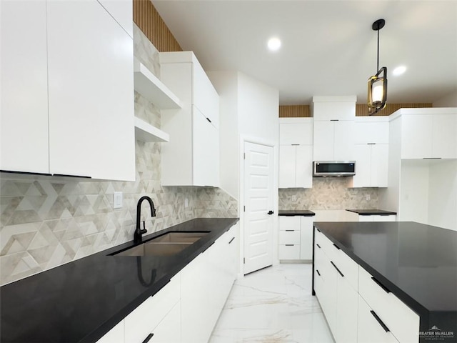 kitchen featuring a sink, stainless steel microwave, marble finish floor, and modern cabinets