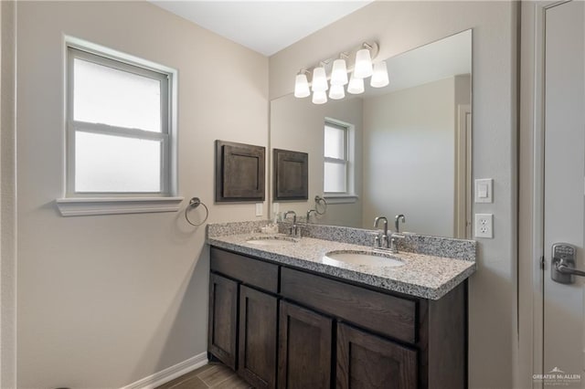full bath featuring double vanity, a sink, and baseboards