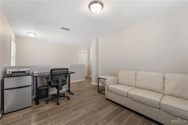 office area with baseboards, visible vents, and wood finish floors