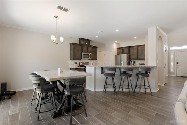 dining space with recessed lighting, wood finish floors, baseboards, arched walkways, and visible vents