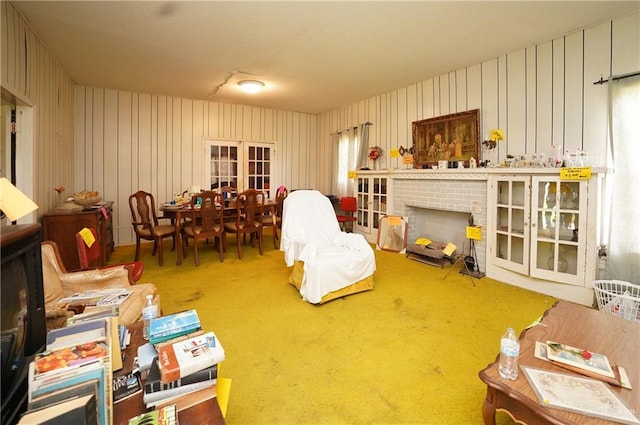 living area with wooden walls, french doors, and carpet