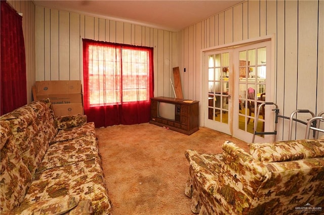 living room featuring carpet, french doors, and wood walls