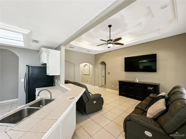 700 Via Cantera Dr, San Juan, TX 78589 - living room with arched walkways, a tray ceiling, light tile patterned floors, baseboards, and ceiling fan