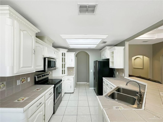 700 Via Cantera Dr, San Juan, TX 78589 - kitchen with stainless steel appliances, tile counters, a sink, tasteful backsplash, and white cabinets