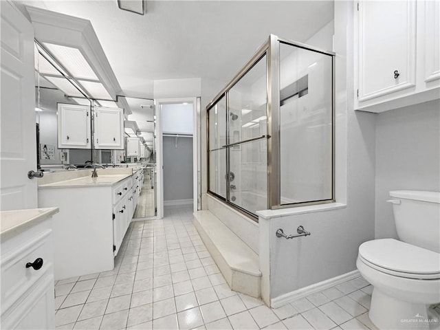 full bathroom with vanity, bath / shower combo with glass door, tile patterned floors, and toilet