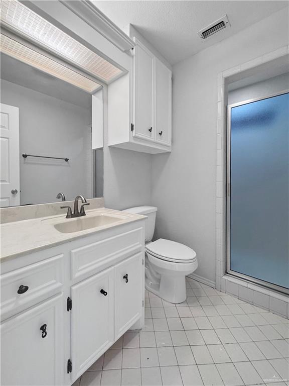 bathroom featuring tile patterned flooring, vanity, an enclosed shower, toilet, and a textured ceiling