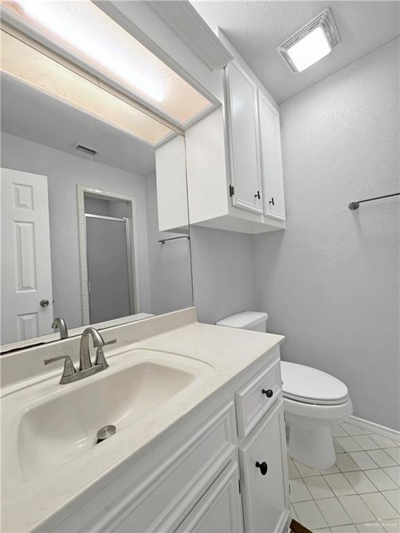 bathroom with an enclosed shower, vanity, tile patterned floors, and toilet