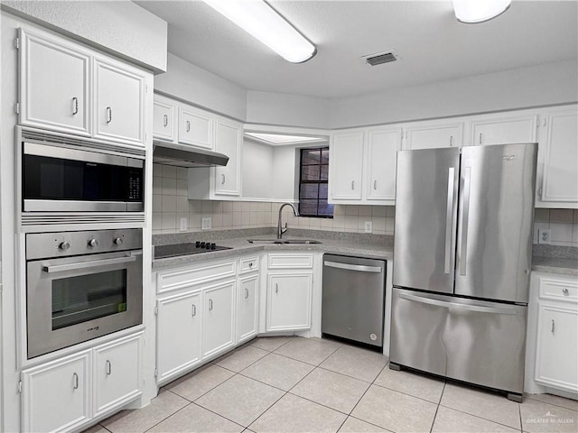 kitchen with light tile patterned floors, appliances with stainless steel finishes, sink, and white cabinets