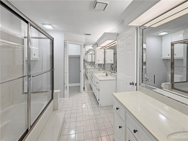 full bathroom with toilet, vanity, bath / shower combo with glass door, and tile patterned flooring