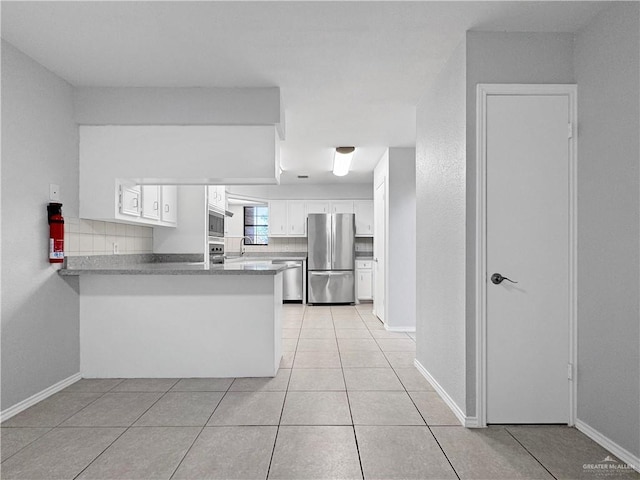 kitchen with tasteful backsplash, white cabinets, light tile patterned floors, kitchen peninsula, and stainless steel appliances