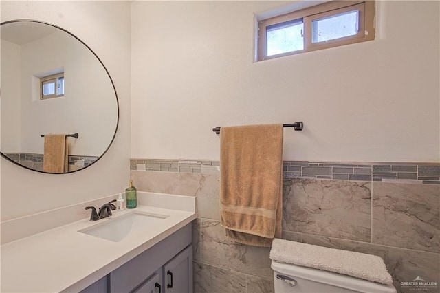 bathroom with vanity, tile walls, and toilet